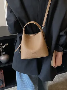 Borsa a secchiello marrone in grana litchi con manico e tracolla in set lifestyle