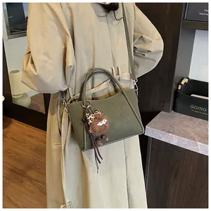 Olive green bucket bag featuring a soft leather texture and cute plush bear charm