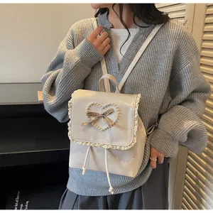 Detail view of cream-colored mini backpack featuring lace edges and pearl heart pattern
