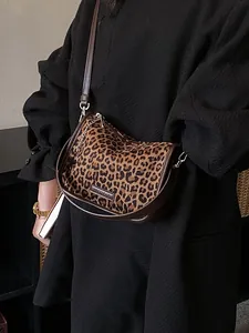Chic leopard print crossbody bag with gold chain worn by a model in a black coat