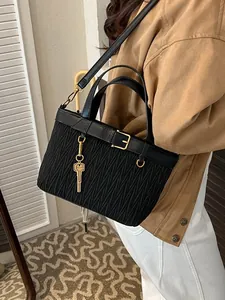 Minimalist black pleated bucket bag with gold key charm and leather top handle