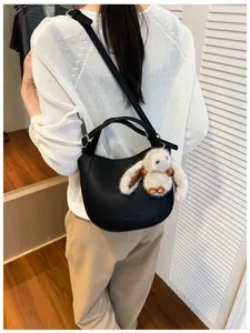 Rear view of black pebble leather hobo bag with adjustable strap and cute rabbit pendant