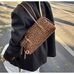 Détail du sac cylindre léopard avec lanières en cuir et breloque donut au soleil