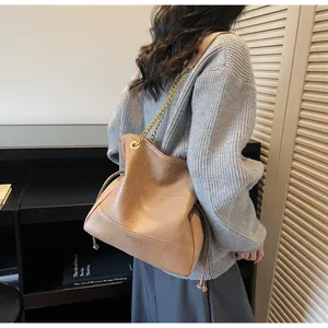 Detail of camel bucket bag featuring quilted stitching and golden chain strap