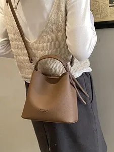 Secchiello marrone in pelle litchi con nappe indossato da modella con maglione