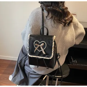 Close-up of black leather backpack with lace trim, pearl heart, and bow details