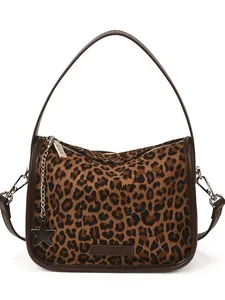 Leopard print crossbody bag with brown leather trim and star pendant on white background