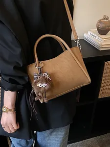 Minimalist khaki bucket bag with plush leopard bow charm for daily wear