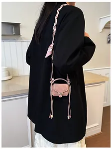 Detail of pink mini crossbody bag with beaded strap and silver snap button on black suit