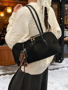 Sac à épaule chic en daim noir avec fermetures dorées et détail de pompon en hiver