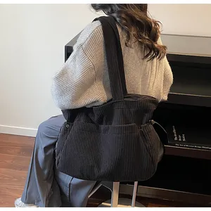 Detailed texture of black corduroy tote bag showing wide shoulder strap and metal eyelet