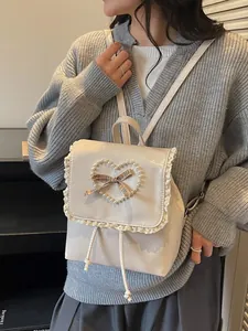 Chic cream white lace backpack for women with pearl heart and bow detail on model