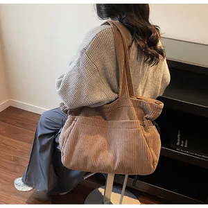Detail of brown corduroy tote bag featuring adjustable side drawstrings and large capacity