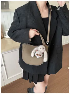 Detail of taupe litchi grain leather bucket bag with cute plush rabbit charm and logo