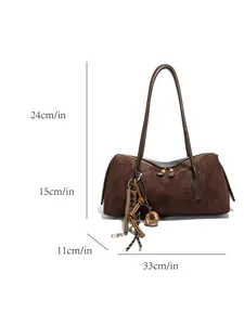 Sac cabas en daim marron café avec breloques ludiques sur un fond blanc épuré