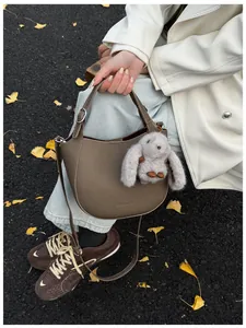 Detail of dark brown leather bucket bag with brand logo and cute plush rabbit charm