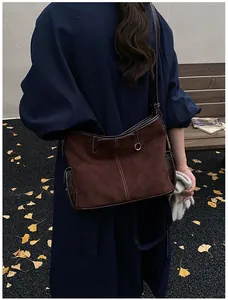 Detail of brown suede tote bag with white contrast stitching and leather panels