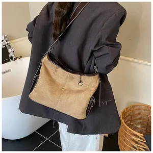 Detail showing the brown suede tote bag worn on shoulder for a stylish commuter look
