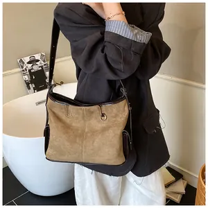 Detail of retro suede tote bag with leather piping and metal ring decoration on shoulder strap