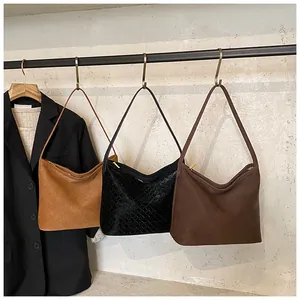 Three woven hobo bags in beige black and brown hanging on a metal rack