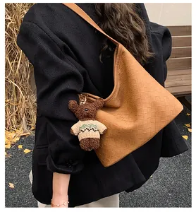 Brown woven texture hobo bag detail with a cute teddy bear charm on wide shoulder strap