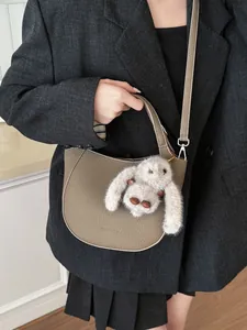 Taupe pebbled leather half-moon bucket bag with plush rabbit charm and shoulder strap