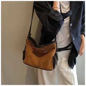 Detail of retro suede and leather tote bag featuring metal ring buckle and side pockets