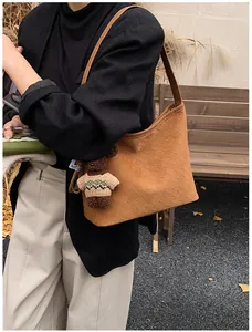 Detail of brown woven leather tote with a cute plush bear charm on autumn background