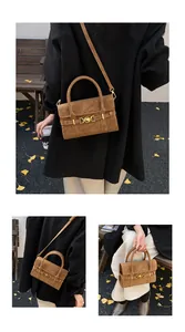 Vista street style di una borsa a tracolla in pelle scamosciata marrone con fibbia dorata