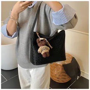 Detail of black woven leather tote bag featuring a cute teddy bear plush charm