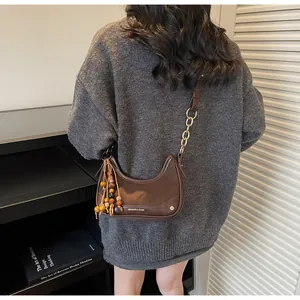 Close-up of brown half-moon bag with chain strap and boho wooden bead detail
