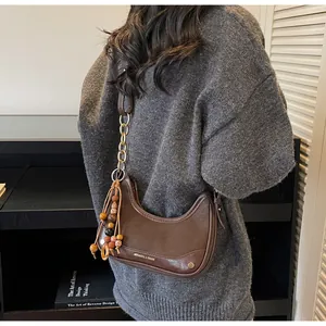 Detail of dark brown faux leather bag with gold chain strap and wooden bead accessory