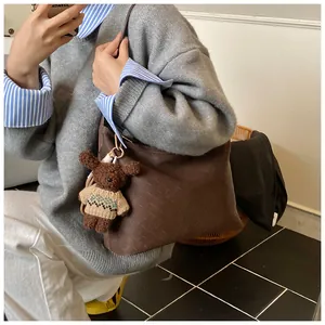 Detail of dark brown woven leather tote bag featuring a cute plush bear charm accessory