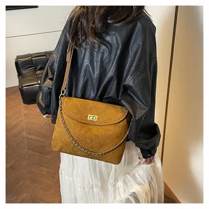 Close-up of quilted mustard yellow shoulder bag with metal chain and turn-lock closure