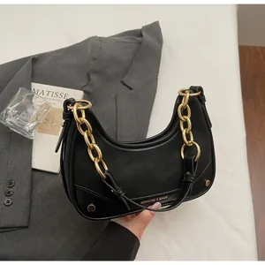 Detail of black faux leather crescent bag with chunky gold chain and metallic branding