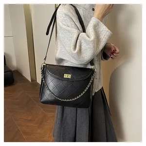 Close-up of black quilted shoulder bag featuring gold metal twist lock and chain strap
