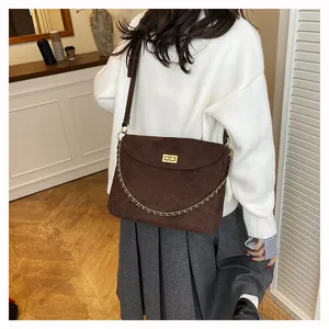 Detail of dark brown quilted crossbody bag with gold chain and metal twist lock