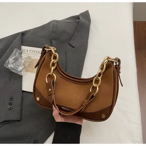 Detail of a brown crescent shoulder bag with gold chain and matte leather textures