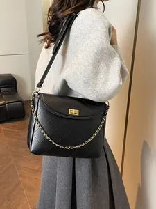 Black quilted tote bag with gold chain and turn-lock closure on model for 2025 fashion
