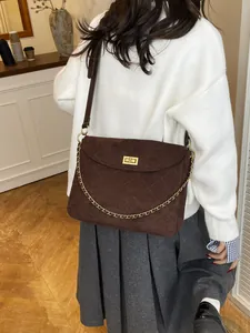 Dark brown quilted suede messenger bag with gold chain strap and square buckle on model