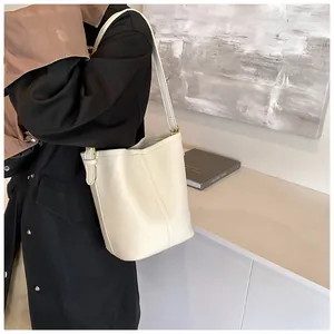 Détails de la texture cuir litchi blanc et boucle dorée du sac seau élégant pour femme