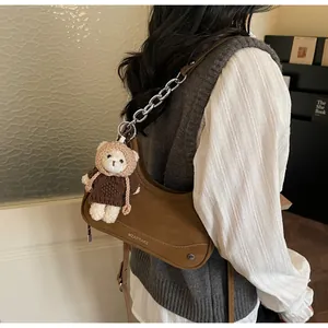 Detail der braunen Vintage-Hobo-Tasche mit Silberkette und weißem Bärenanhänger