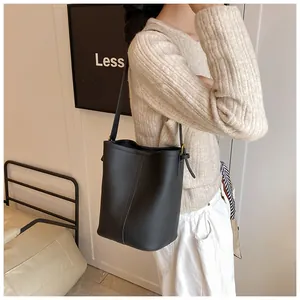 Détail du sac seau en cuir noir à grain litchi avec coutures verticales et bandoulière