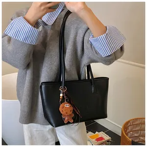 Dettaglio della borsa tote in pelle nera con logo sbalzato e ciondolo di peluche