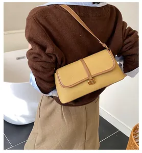 Détail du sac baguette en cuir jaune avec boucle en C dorée et fine bandoulière élégante