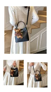 Detail of black pebbled leather bucket bag with silver twist lock and bear charm accessory