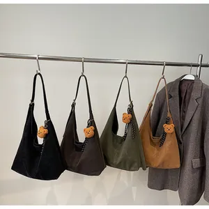 Detailweergave van grote draagtassen in zwart, groen en bruin met schattige beerhangers