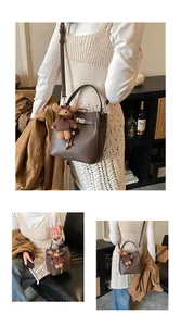 Detail of dark brown lychee leather bucket bag with metal lock and cute bear charm