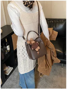 Detailed shot of dark brown litchi grain leather bucket bag with cute plush bear charm