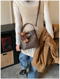 Detail of dark brown lychee pattern leather bucket bag with a cute bear plush charm